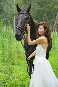 树林里漂亮的青年女人牵着马图片