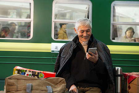 在火车站台上用手机的老人图片