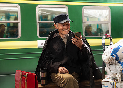 在火车站台上用手机的老人图片