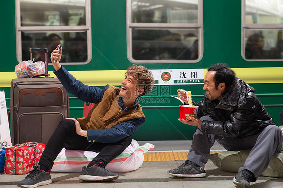 两名男子在火车月台上看手机图片
