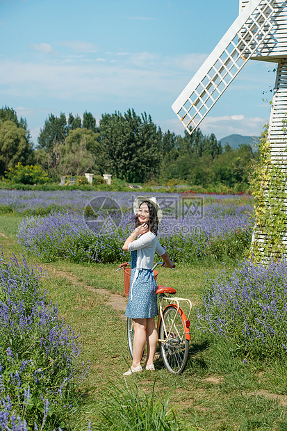 推着自行车的青年女人站在花海里图片