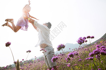 父女站在花丛里父亲抱着女儿在花丛中玩耍背景