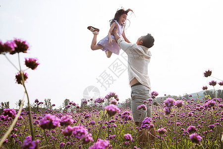 父女站在花丛里父亲抱着女儿在花丛中玩耍背景