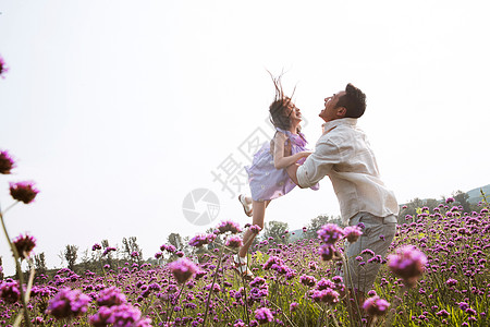 父亲抱着女儿在花丛中玩耍图片