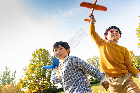 小孩嬉戏拿着玩具飞机在公园玩耍的男孩背景