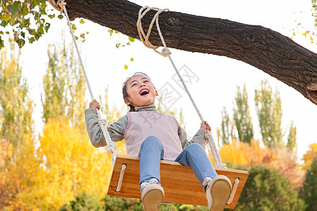 小女孩在荡秋千快乐的小女孩在公园里荡秋千背景
