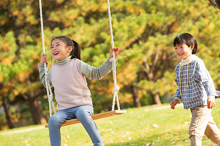 小孩嬉戏在公园里荡秋千的快乐儿童背景