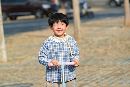 快乐的男孩在户外玩滑板车图片
