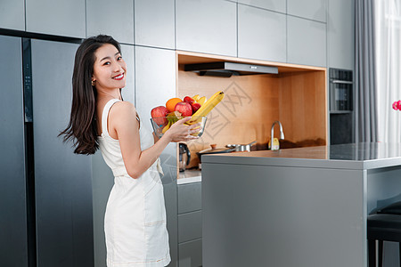 养生地产拿着水果的青年女人站在冰箱前背景