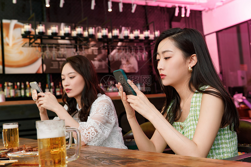 在酒吧里玩手机的青年女人图片