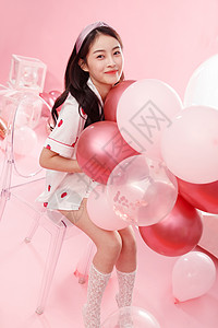 粉色椅子漂亮的年轻女孩和气球背景