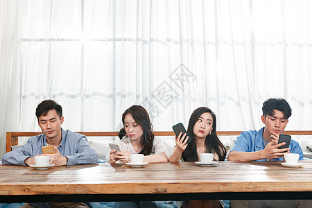 青年朋友坐在一排玩手机图片