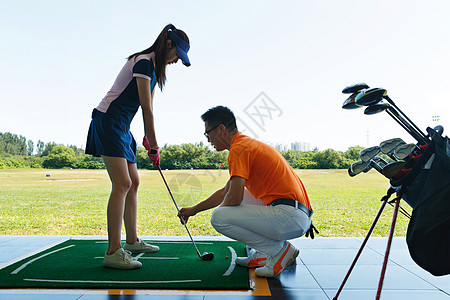 练习场上教练指导青年女人打高尔夫高清图片