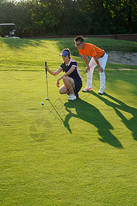球场上教练指导青年女人打高尔夫图片