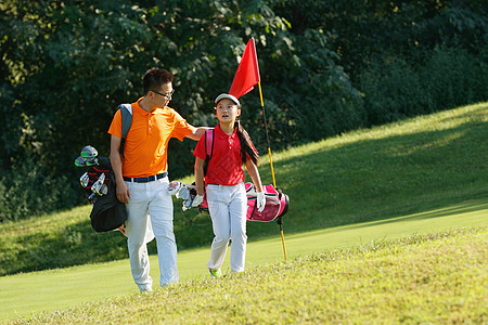 背着包的人球场上教练和学生背着高尔夫球包行走背景