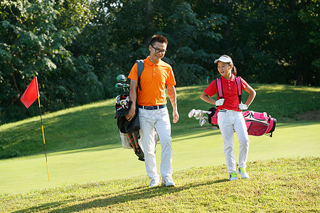 行走的人球场上教练和学生背着高尔夫球包行走背景