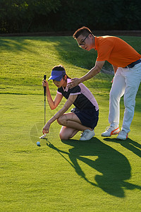 球场上教练指导青年女人打高尔夫图片