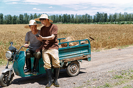 农民坐在三轮车上使用手机高清图片