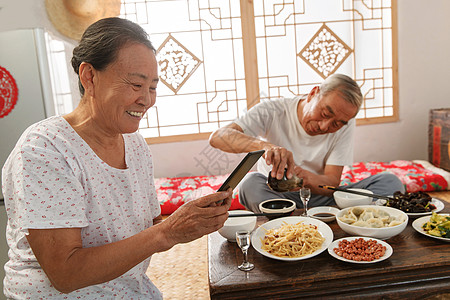 老年夫妇在家里吃饭看手机高清图片