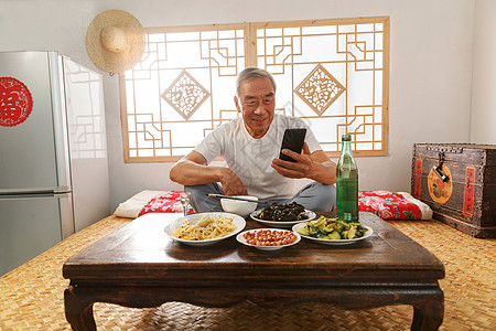 老年人坐在家里吃饭看手机图片