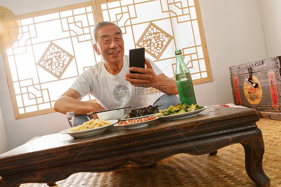 老年人坐在家里吃饭看手机图片