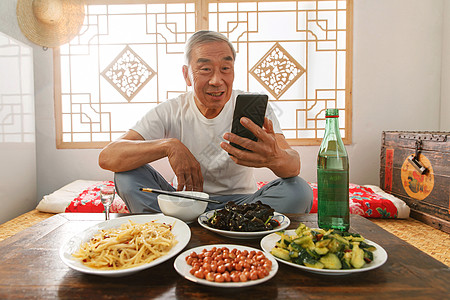 白酒酒瓶老年人坐在家里吃饭看手机背景