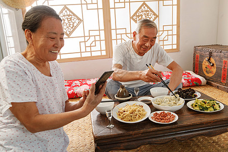 老年夫妇在家里吃饭看手机高清图片