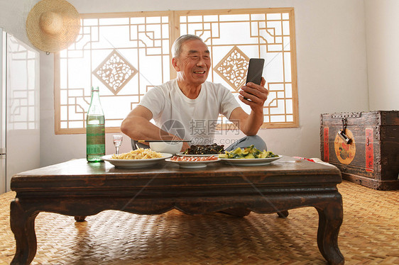 老年人坐在家里吃饭看手机图片