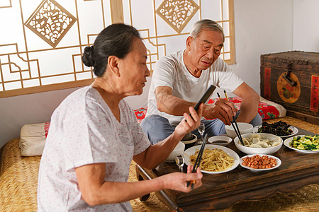 老年夫妇在家里吃饭看手机高清图片