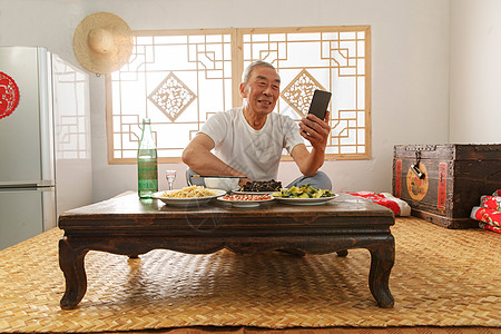 老人吃老年人坐在家里吃饭看手机背景