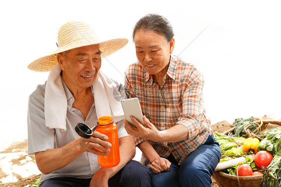 农民夫妇坐在田头看手机图片