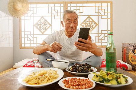 白酒酒瓶老年人坐在家里吃饭看手机背景