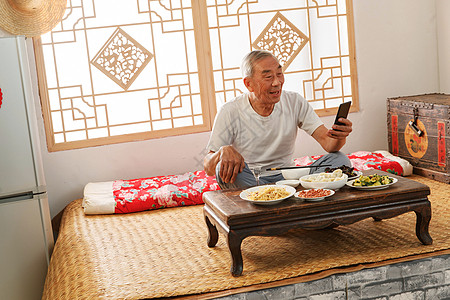 白酒酒瓶老年人坐在家里吃饭看手机背景