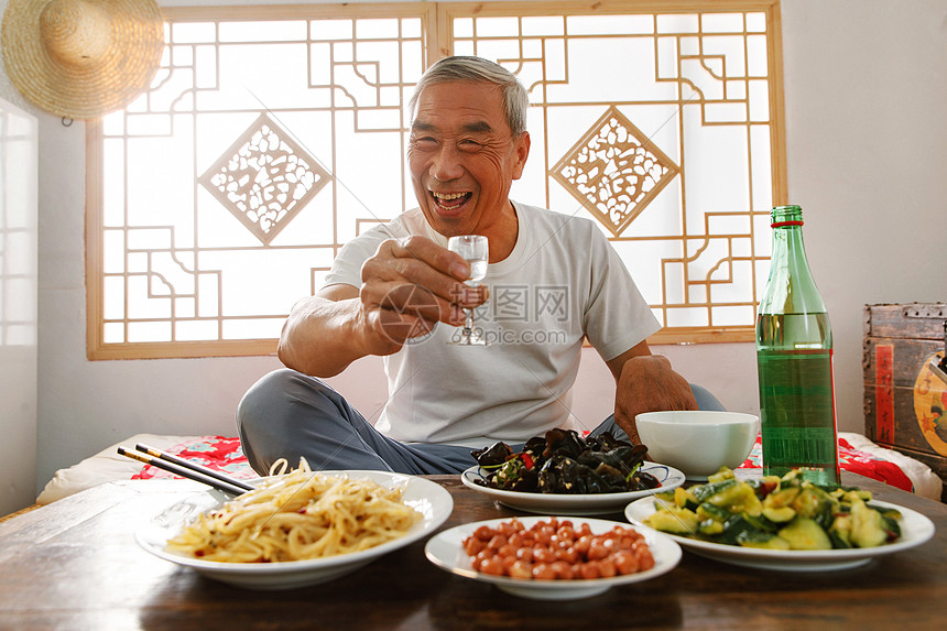 老年人坐在家里喝酒吃饭图片