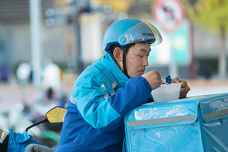 外卖员在街道旁吃饭休息高清图片