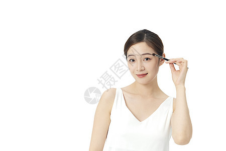 年轻美女使用眉笔化妆背景图片