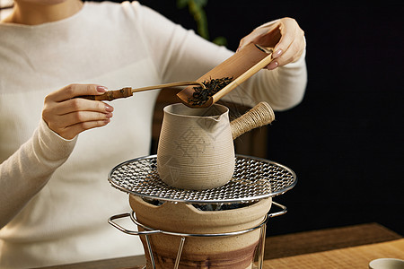 国潮美食往碳炉茶壶里加入茶叶特写背景