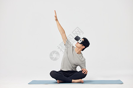 在瑜伽垫上戴着vr眼镜锻炼的男性图片