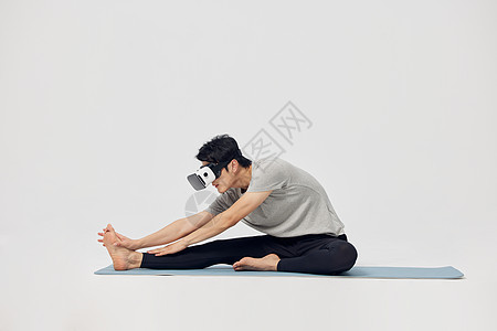 在瑜伽垫上戴着vr眼镜锻炼的男性图片