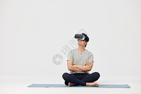 坐在瑜伽垫上操作vr设备的男性图片