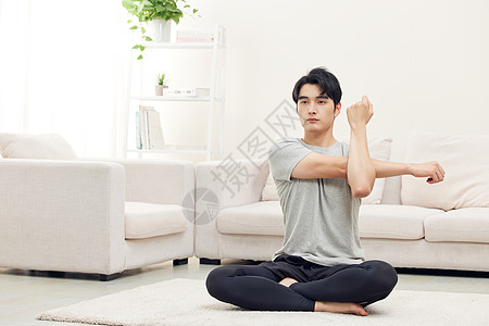 居家坐在瑜伽垫上锻炼热身的男性背景