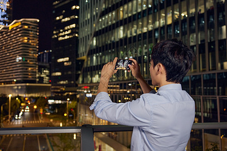 高层建筑夜景夜晚商务男士用手机拍照背景