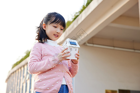 手拿太阳能面板房屋模型的小女孩图片