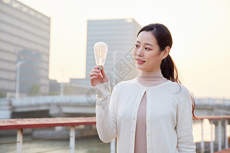 户外手拿节能电灯泡的女性图片