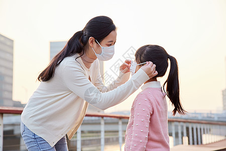 女孩戴口罩户外妈妈帮女儿戴口罩背景