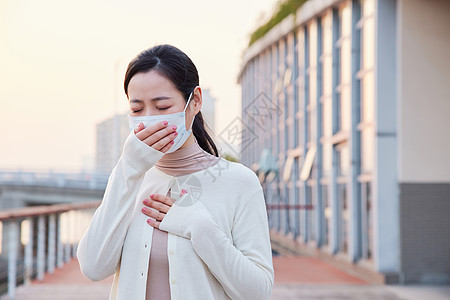 疾病预防室外咳嗽戴口罩的青年女性背景