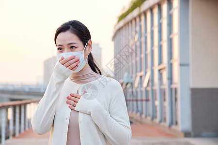 室外咳嗽戴口罩的青年女性图片