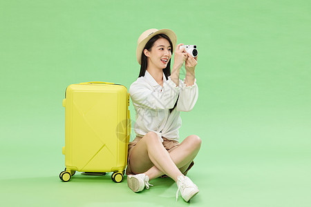 坐在行李箱旁的少女用相机拍照图片
