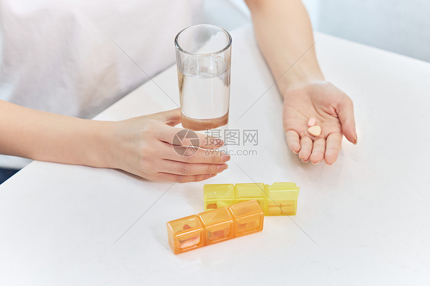 女性生病喝水吃药特写图片