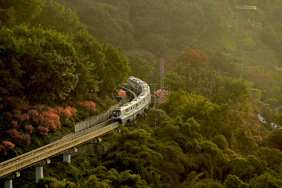 夕阳下穿梭在山间的列车轻轨图片